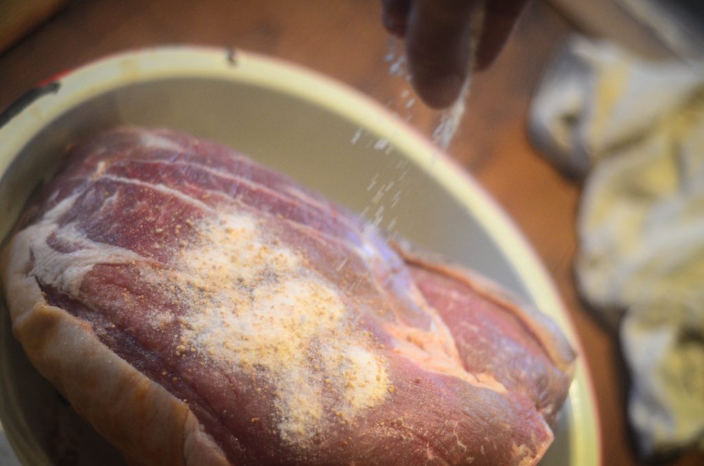 Salting the pork roast for curing. 